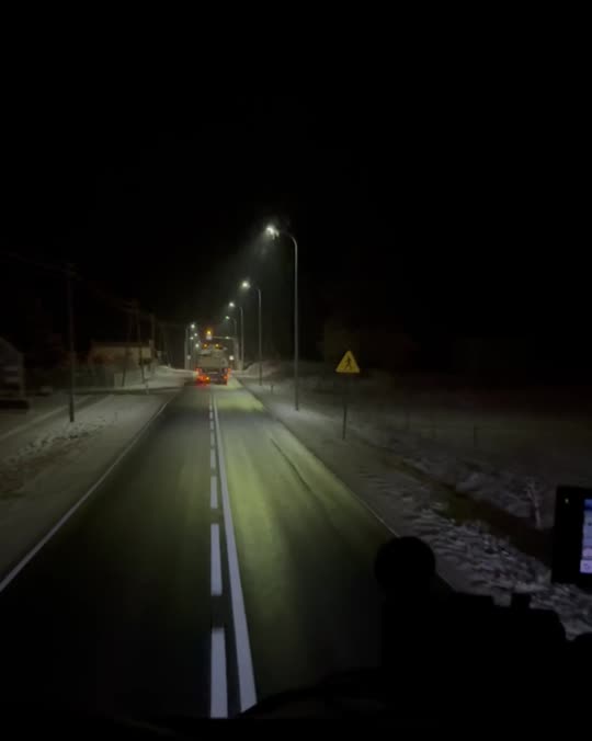 Convoy passing through a town under street lights at night
